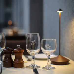 Zwei Weingläser auf gedecktem Tisch mit Salz- und Pfefferstreuer, moderne Tischlampe.