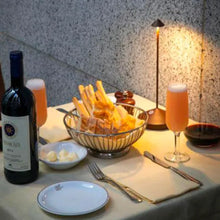 Lade das Bild in den Galerie-Viewer, Esstisch mit Rotwein, Brot, Butter, zwei Gläsern Saft, Tischlampe, elegantes Abendessen.
