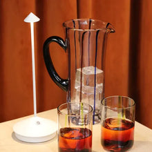 Lade das Bild in den Galerie-Viewer, Karaffe mit Eiswürfeln, zwei Gläser mit Getränk, weiße Tischlampe, modernes Design.
